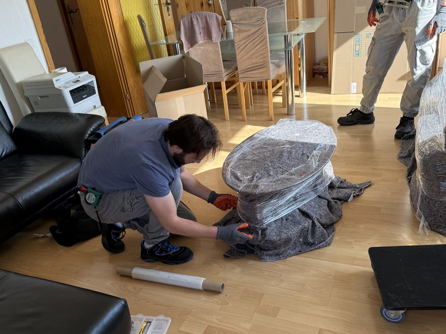 Umzugshelfer wickelt ein Polstermoebel in Schutzfolie