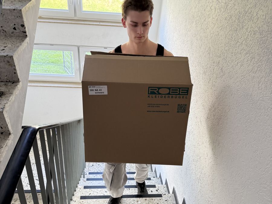 Umzugskarton wird durch ein Treppenhaus getragen