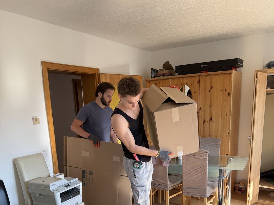 Umzugshelfer raeumen Moebel und Kartons aus einer Wohnung